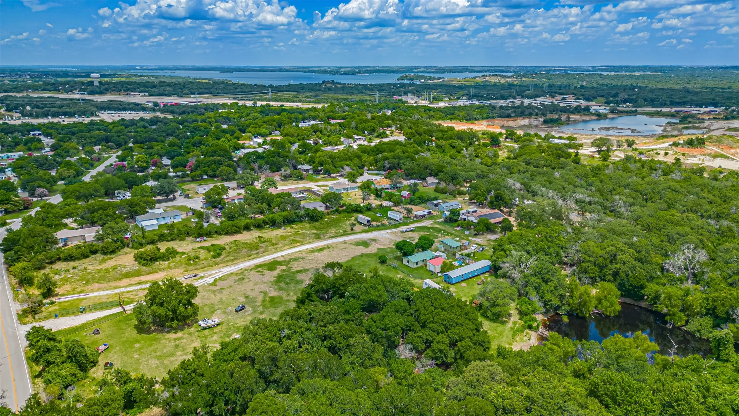 Aerial view of property's location with a nearby body of water and a tree filled landscape