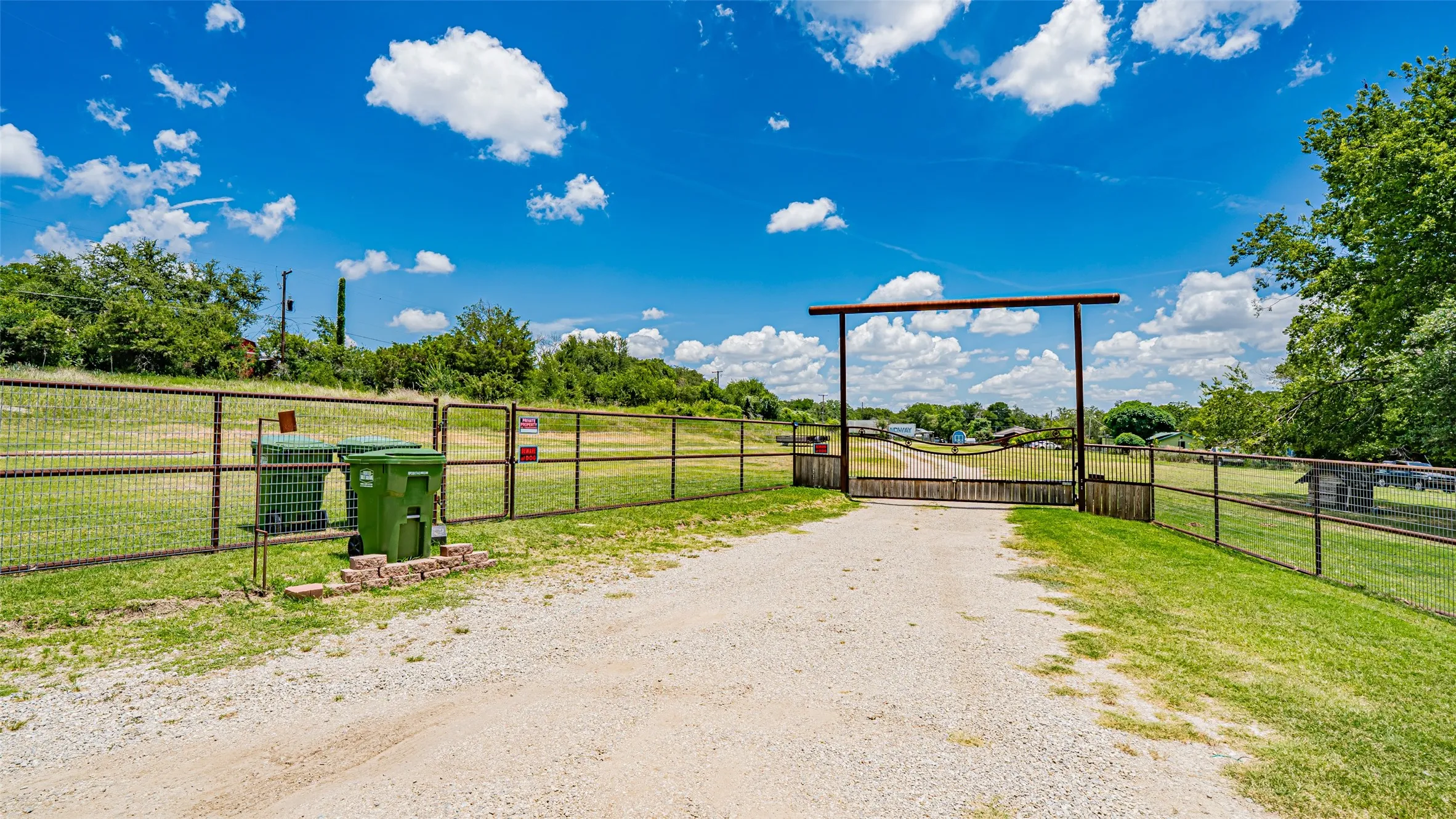 View of dirt / gravel road featuring a gate, a view of rural / pastoral area, and a gated entry