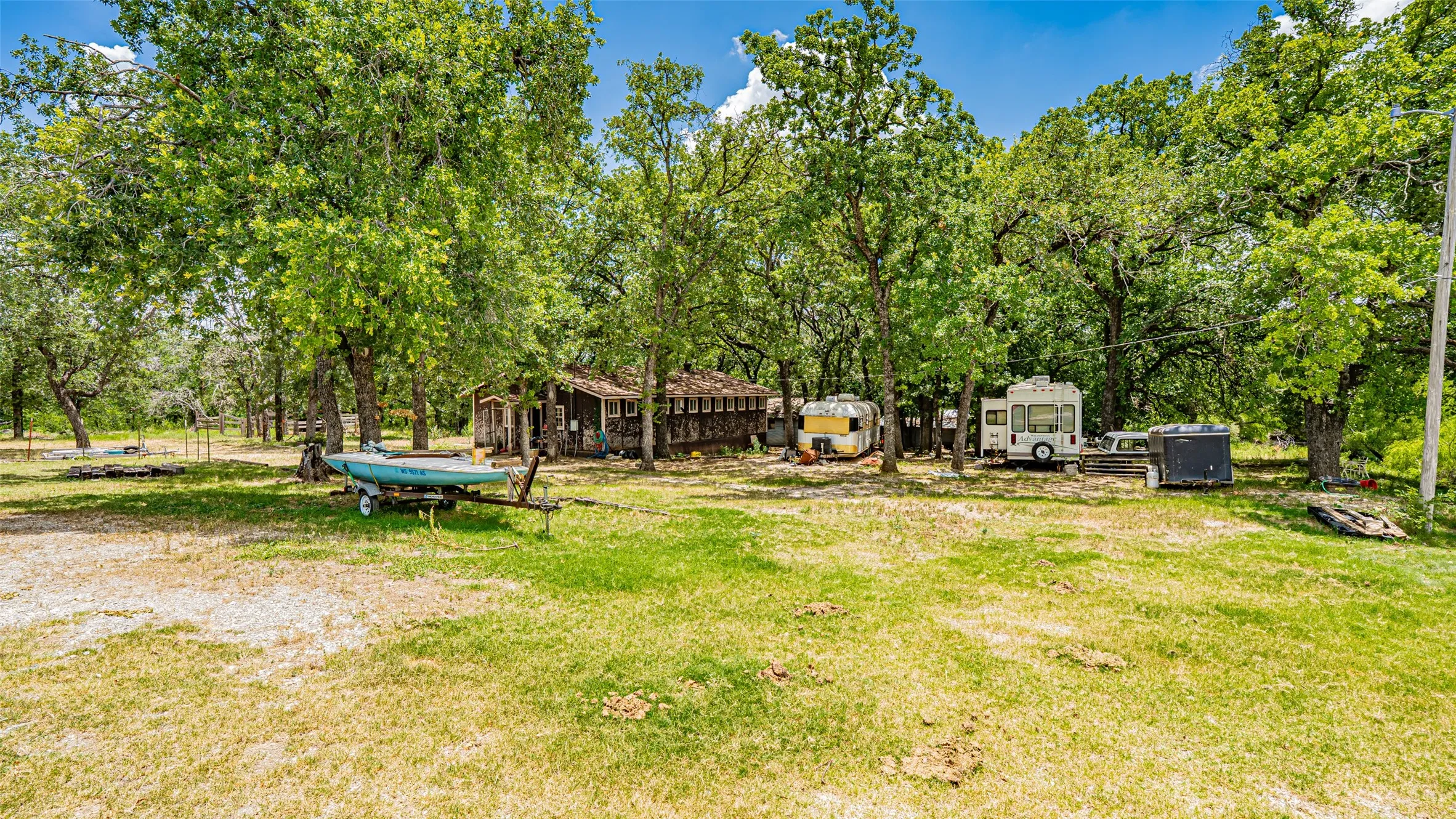 View of green lawn featuring view of wooded area and an outdoor structure