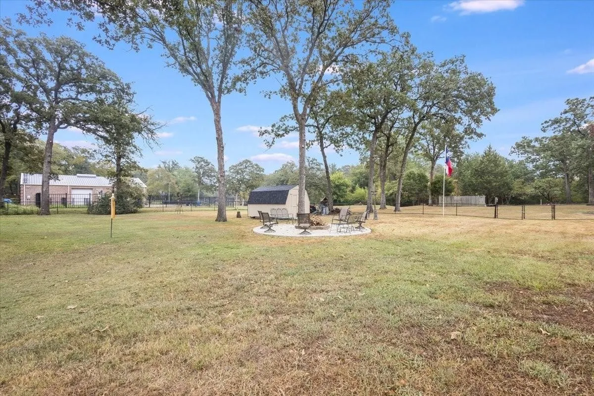 View of yard with an outdoor fire pit, fence, an outdoor structure, and a storage unit