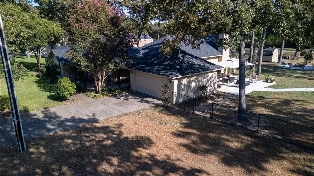 View of front of property with an attached garage, a shingled roof, fence, concrete driveway, and a front lawn