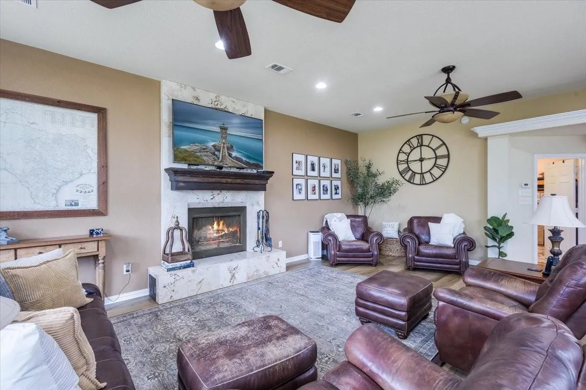 Living area featuring a ceiling fan, a high end fireplace, visible vents, and wood finished floors