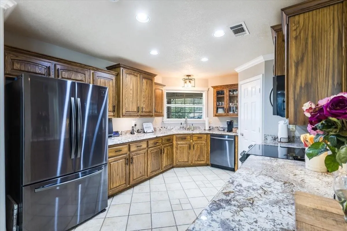 Kitchen featuring appliances with stainless steel finishes, brown cabinetry, visible vents, and a sink