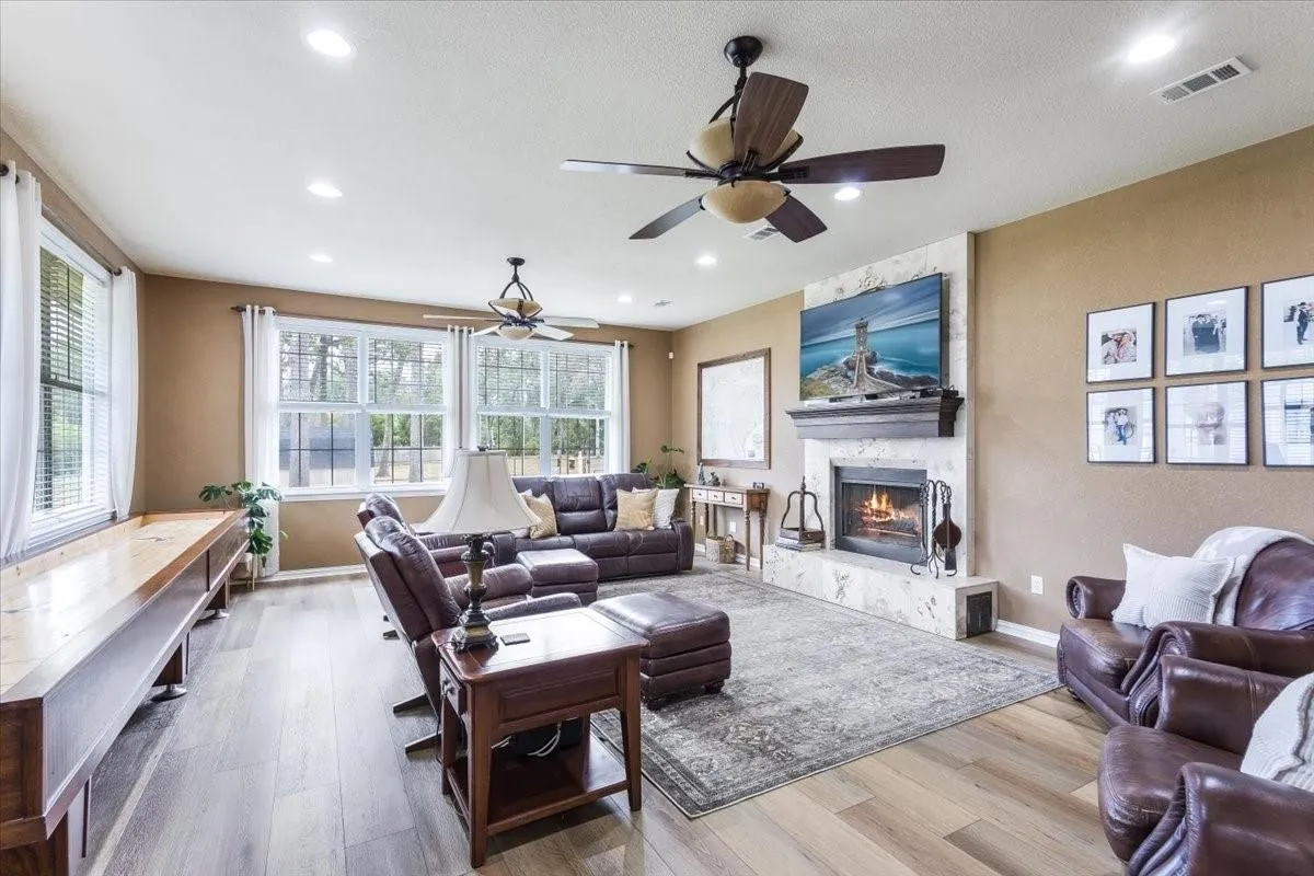 Living area featuring a large fireplace, baseboards, visible vents, and wood finished floors