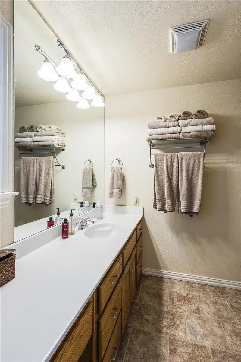 Bathroom featuring a textured ceiling, vanity, visible vents, baseboards, and stone finish flooring