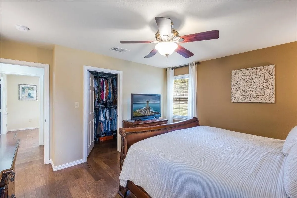 Bedroom featuring baseboards, visible vents, wood finished floors, a spacious closet, and a closet