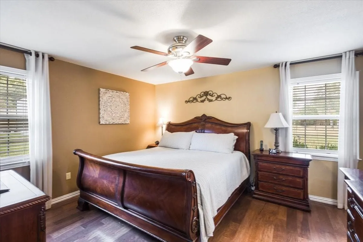 Bedroom with dark wood-style floors, baseboards, and a ceiling fan
