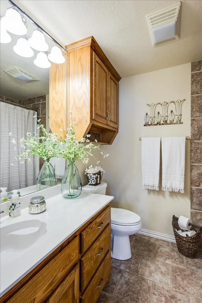 Bathroom featuring toilet, a shower with curtain, visible vents, and a textured ceiling
