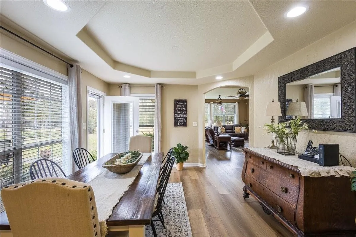 Dining room with a tray ceiling, arched walkways, and wood finished floors