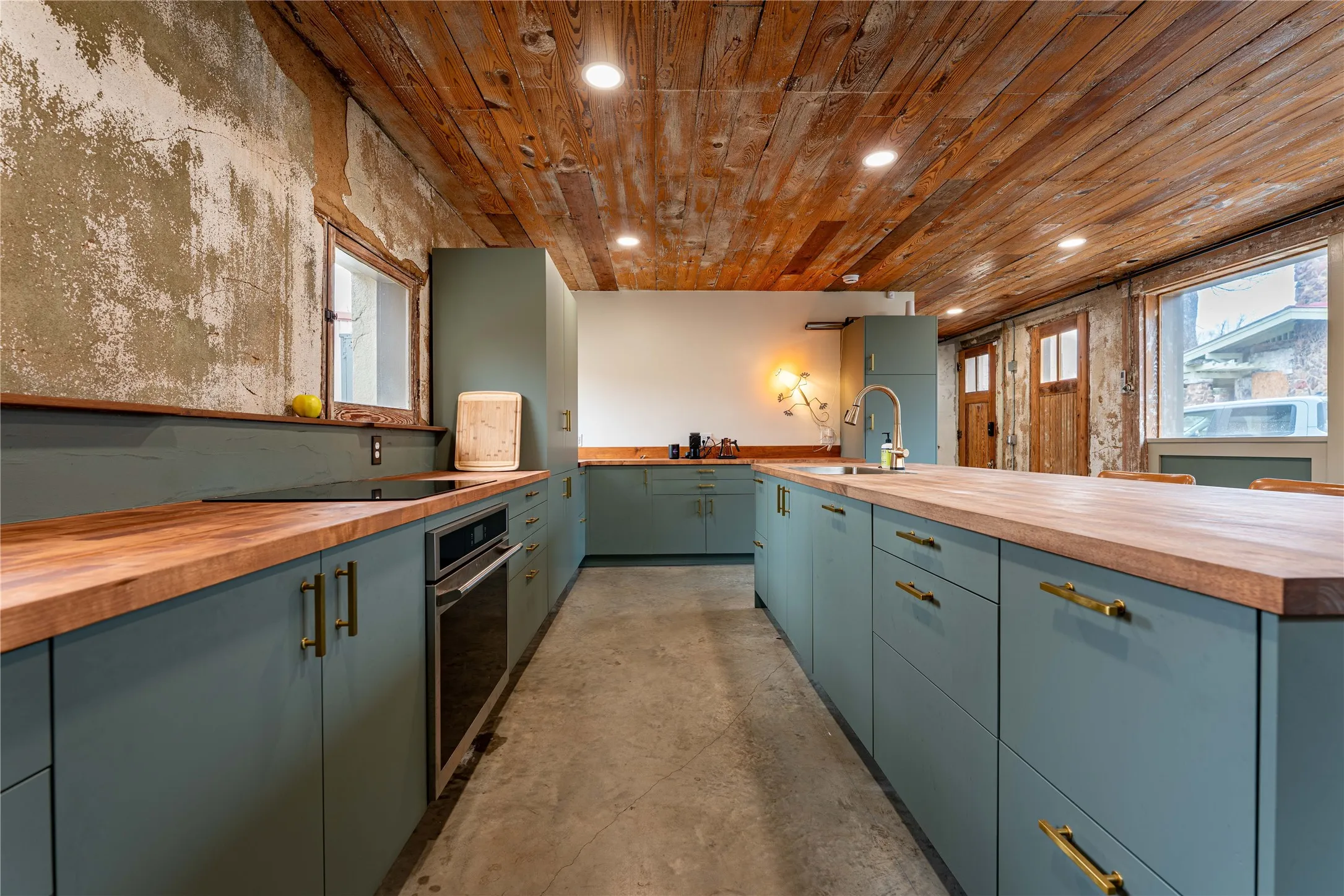 Kitchen with concrete floors, a sink, wood ceiling, wood counters, and stainless steel oven