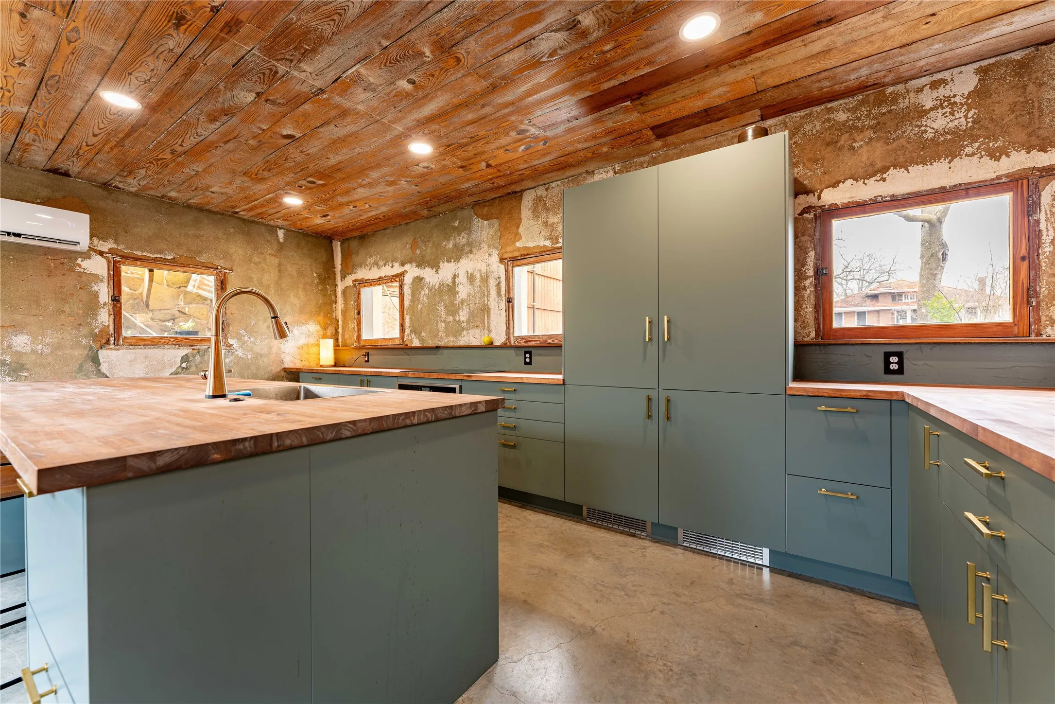 Kitchen with concrete floors, wood counters, wooden ceiling, a wall mounted AC, and a sink