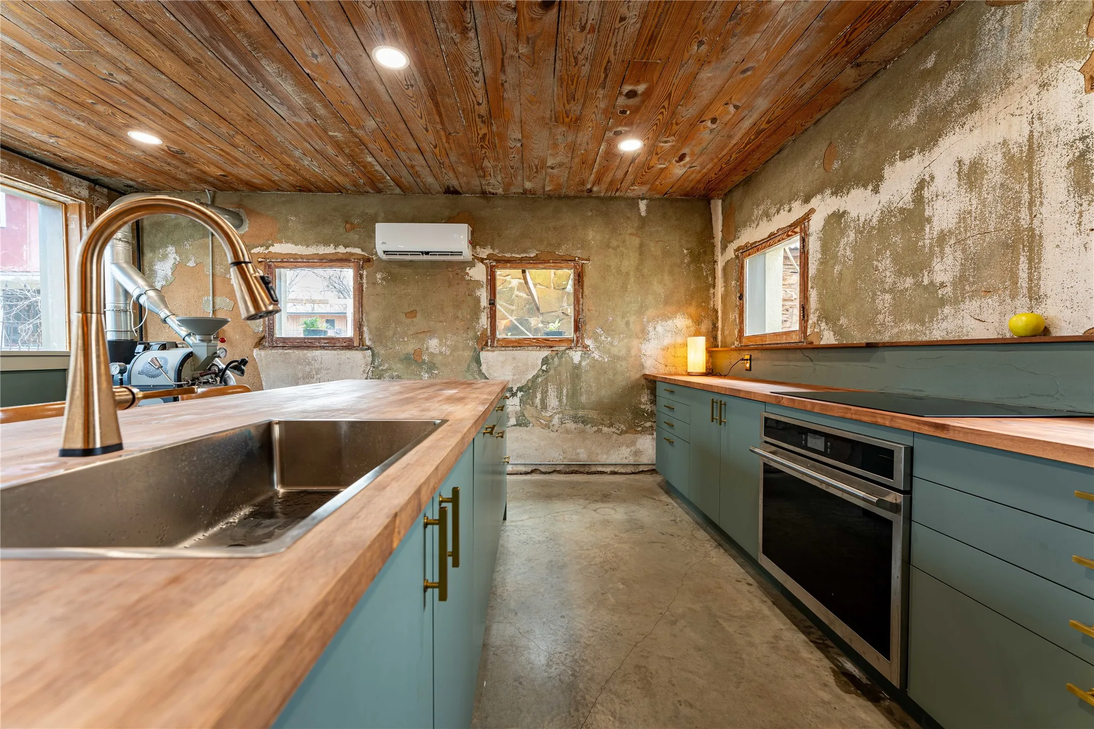 Kitchen featuring green cabinets, oven, a wall unit AC, and butcher block counters