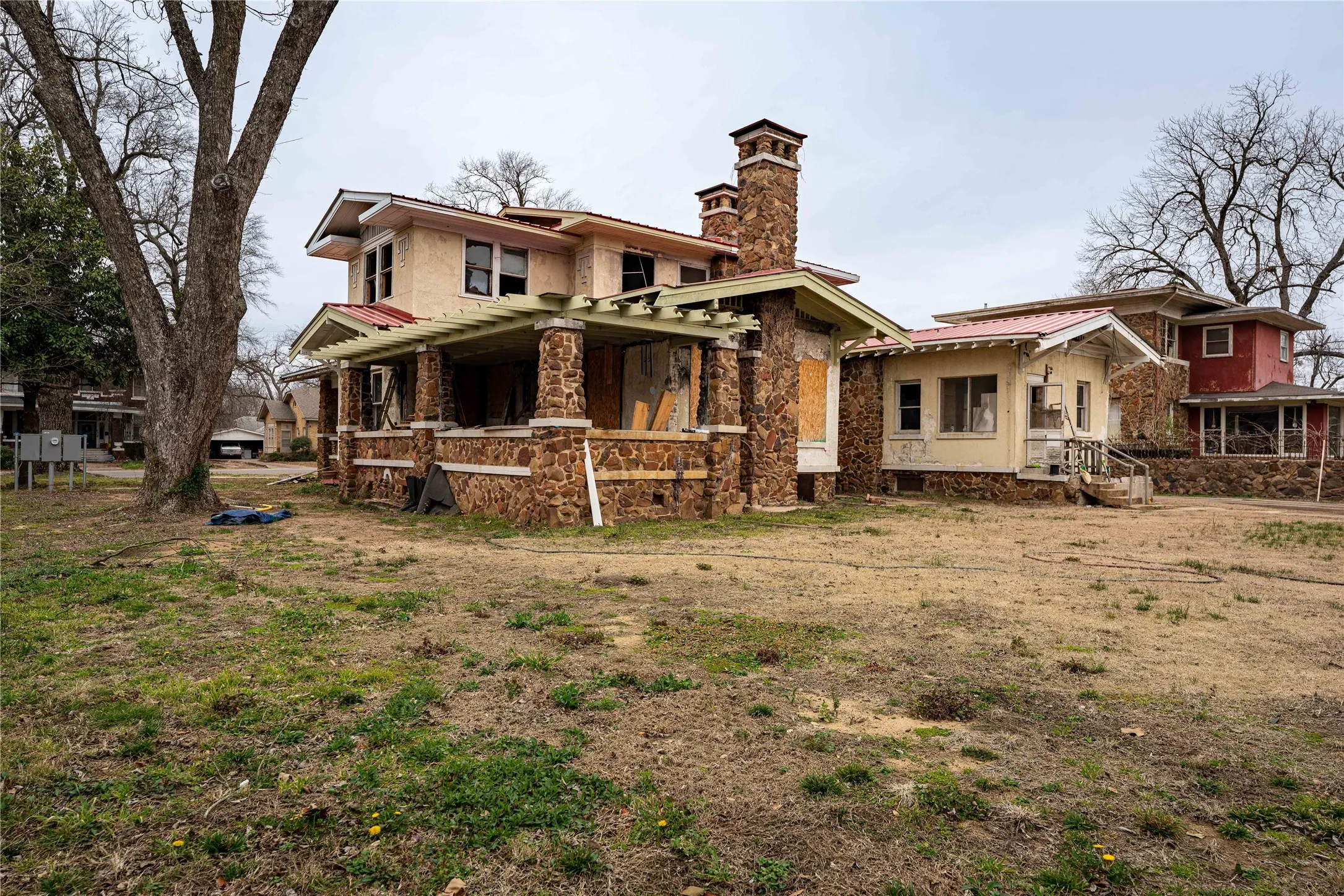 Back of house with metal roof, stone siding, and a chimney
