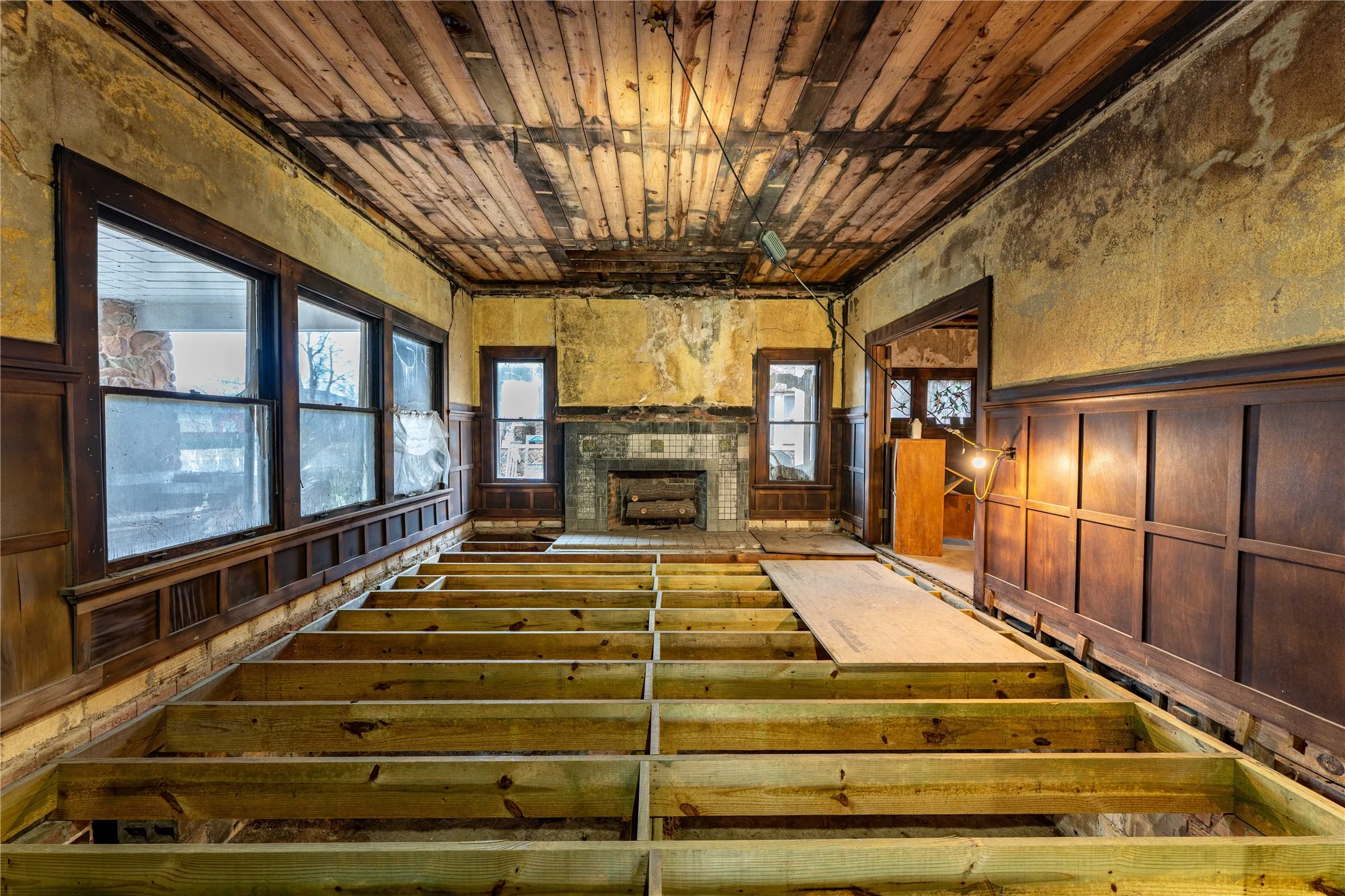Unfurnished living room featuring a wainscoted wall, wooden ceiling, and a fireplace