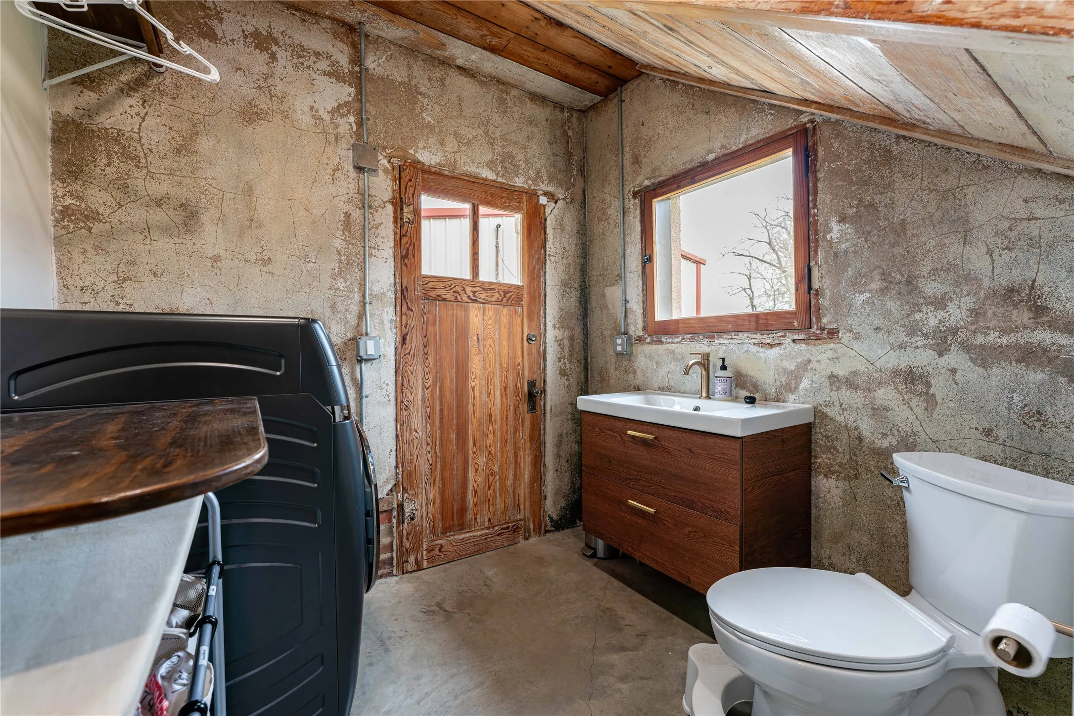 Half bathroom with vanity, lofted ceiling, toilet, and concrete floors