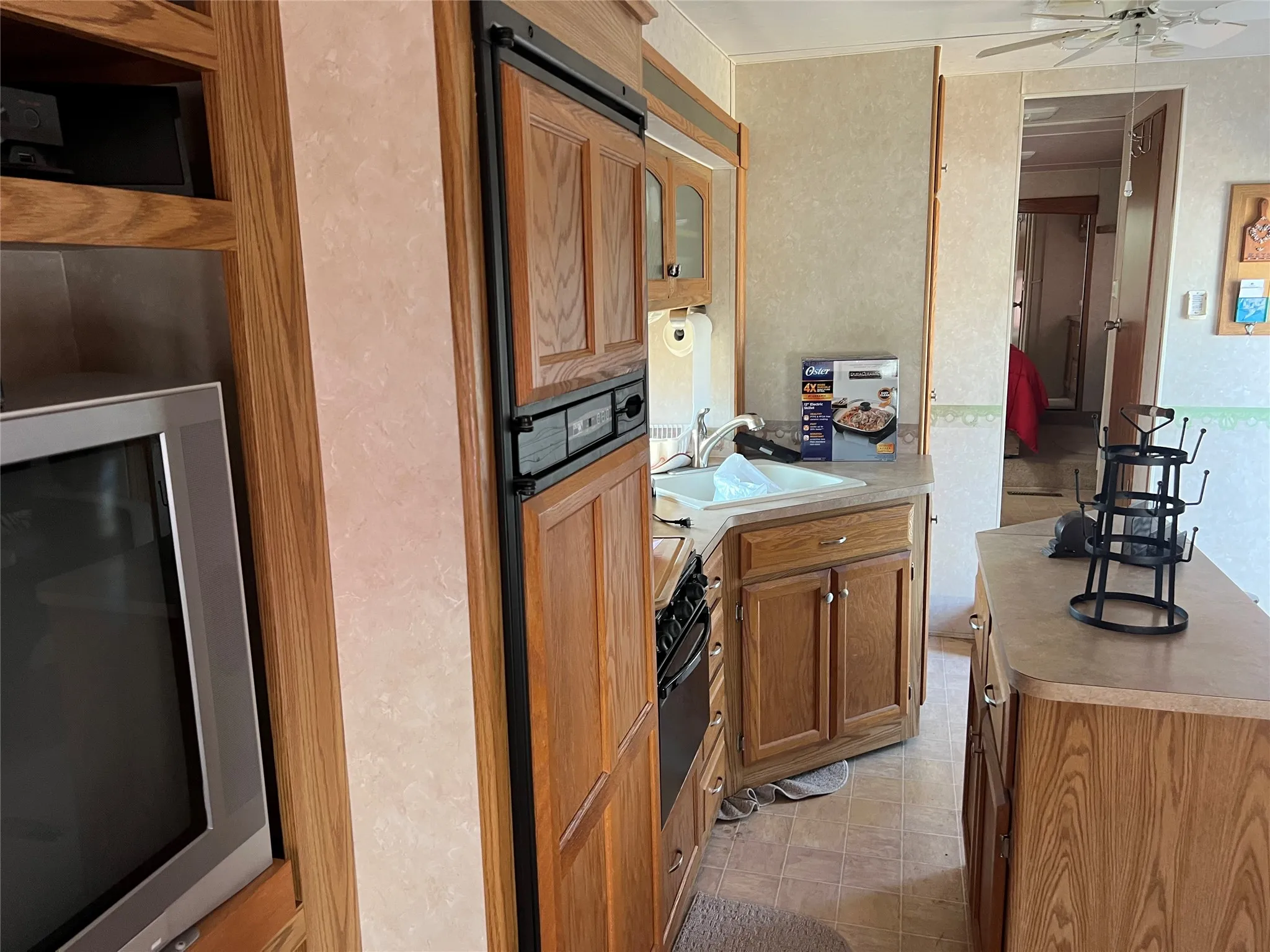 Kitchen featuring wood finish cabinets, ceiling fan, light countertops, and wall oven