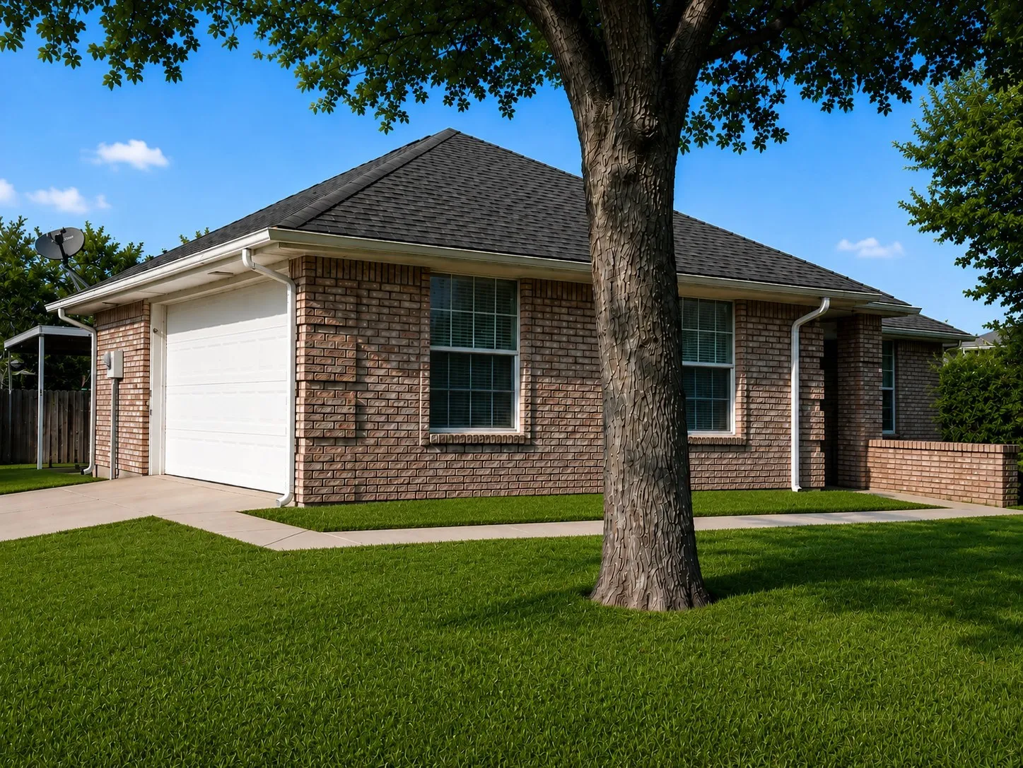 view of side of home featuring driveway, a yard, a shingled roof, a garage, and brick siding