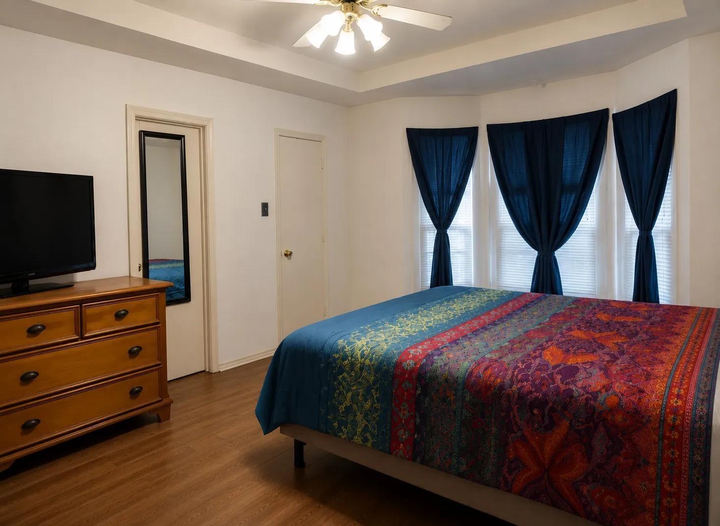 Bedroom featuring a ceiling fan, wood finished floors, and a raised ceiling