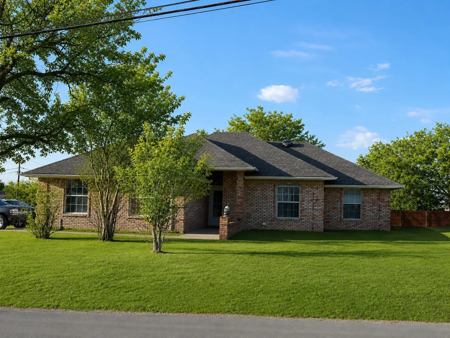 Ranch-style home with brick siding, a shingled roof, a front yard, and fence