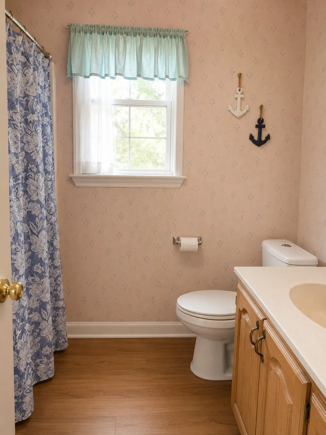 Bathroom with a shower with shower curtain, wallpapered walls, toilet, wood finished floors, and vanity
