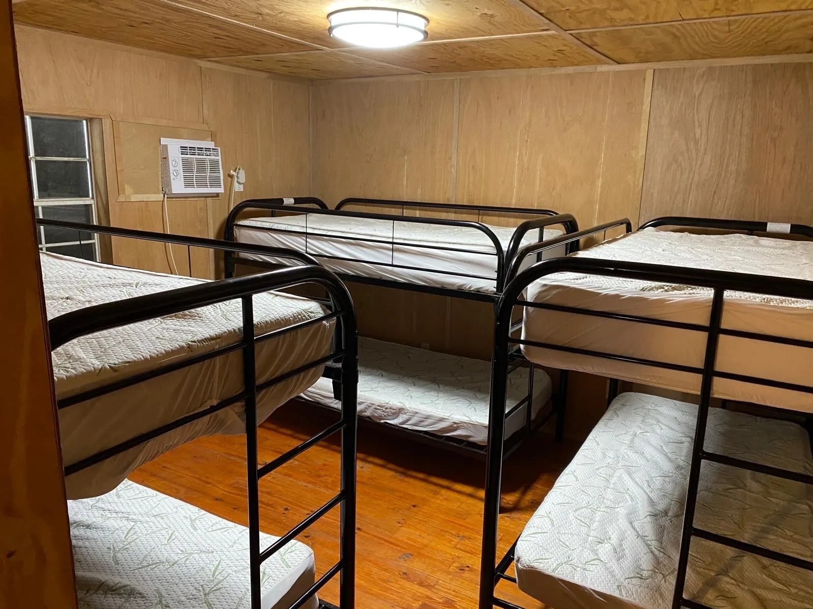 Bedroom with wood finished floors, wooden walls, a wall mounted AC, and wood ceiling