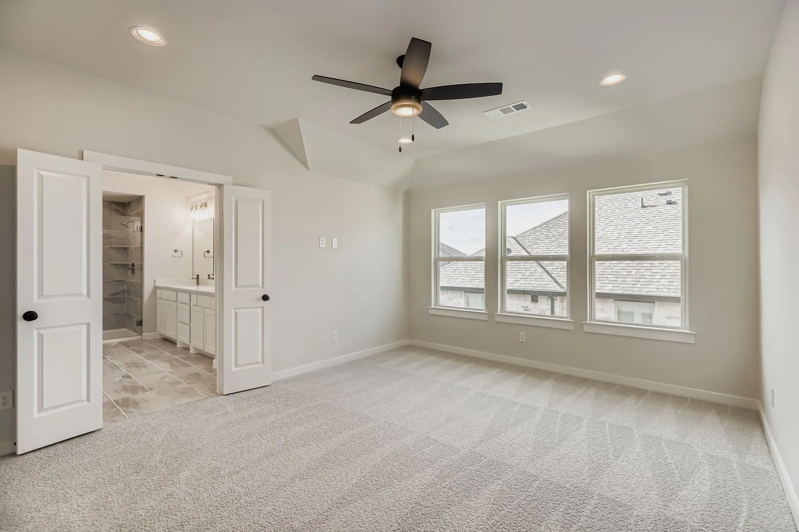 Unfurnished bedroom featuring light carpet, vaulted ceiling, recessed lighting, connected bathroom, and a ceiling fan