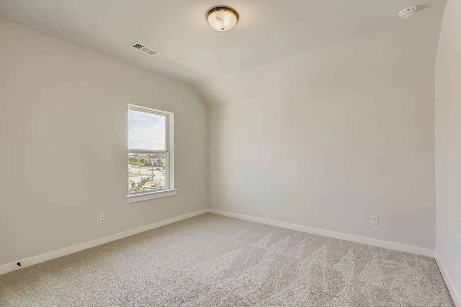Empty room featuring light colored carpet, a smoke detector, and lofted ceiling