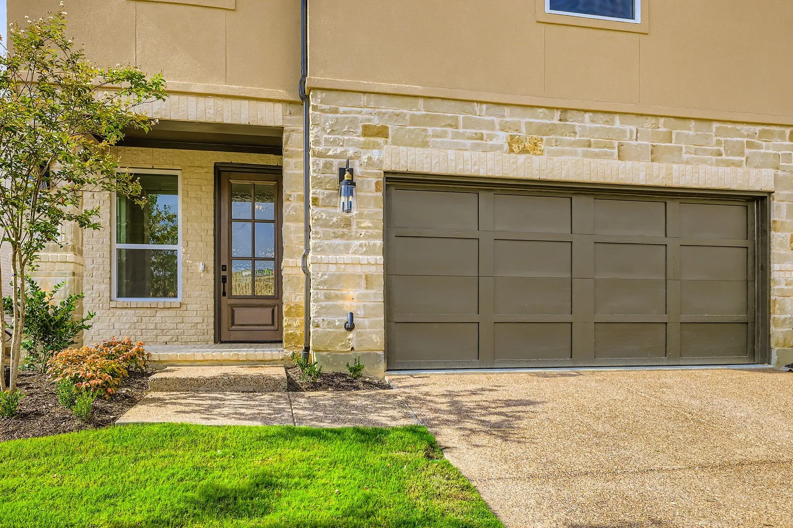Property entrance featuring a garage, driveway, and stone siding