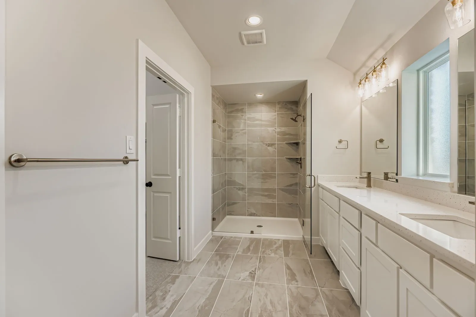 Full bathroom featuring double vanity, a shower stall, marble look tile flooring, and recessed lighting