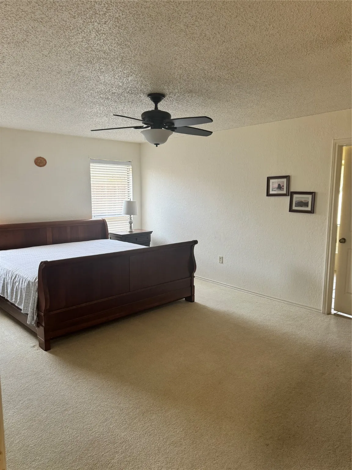 Unfurnished bedroom featuring a textured ceiling, carpet floors, ceiling fan, and a textured wall