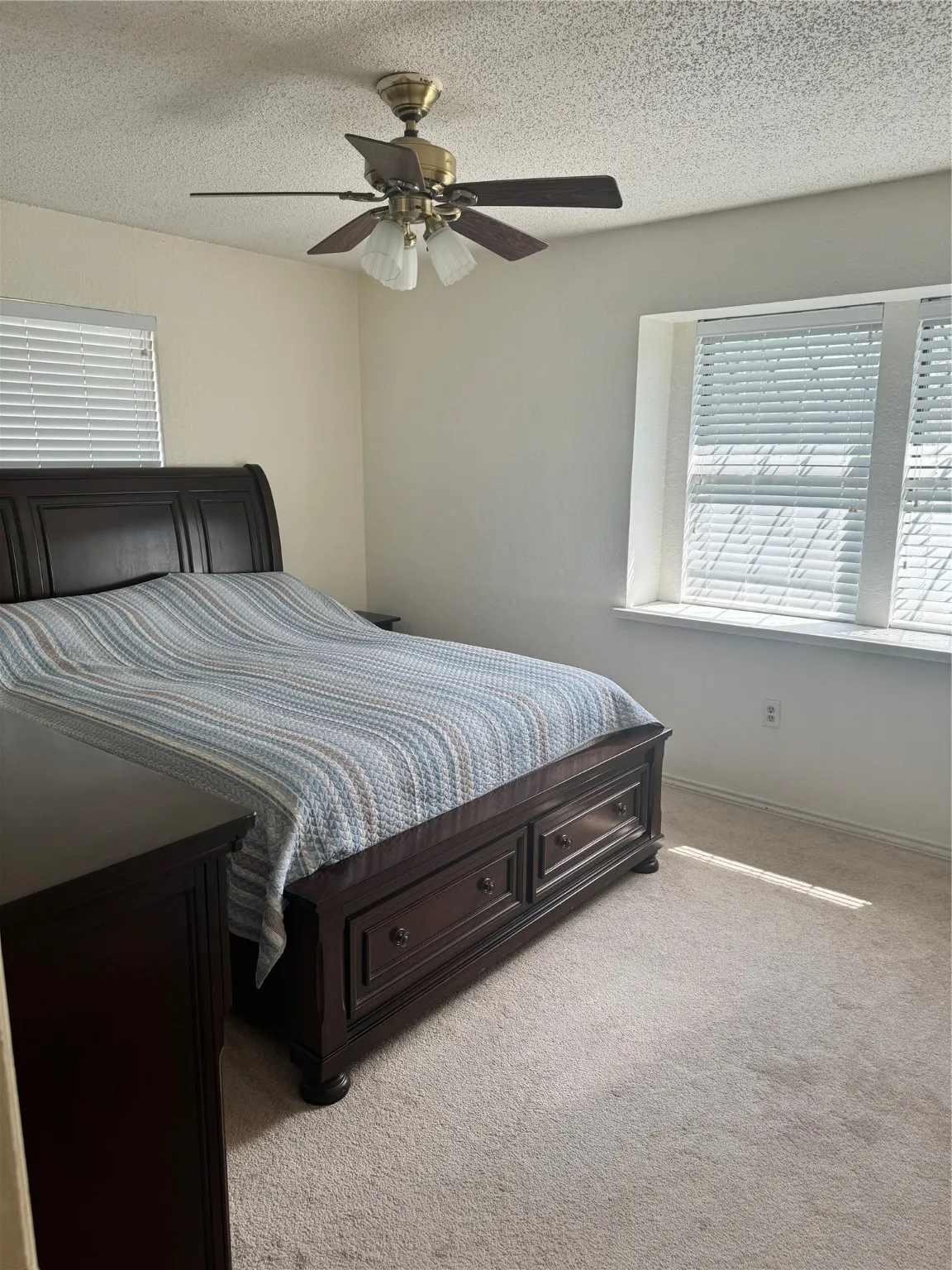 Bedroom featuring baseboards, carpet floors, a textured ceiling, and a ceiling fan