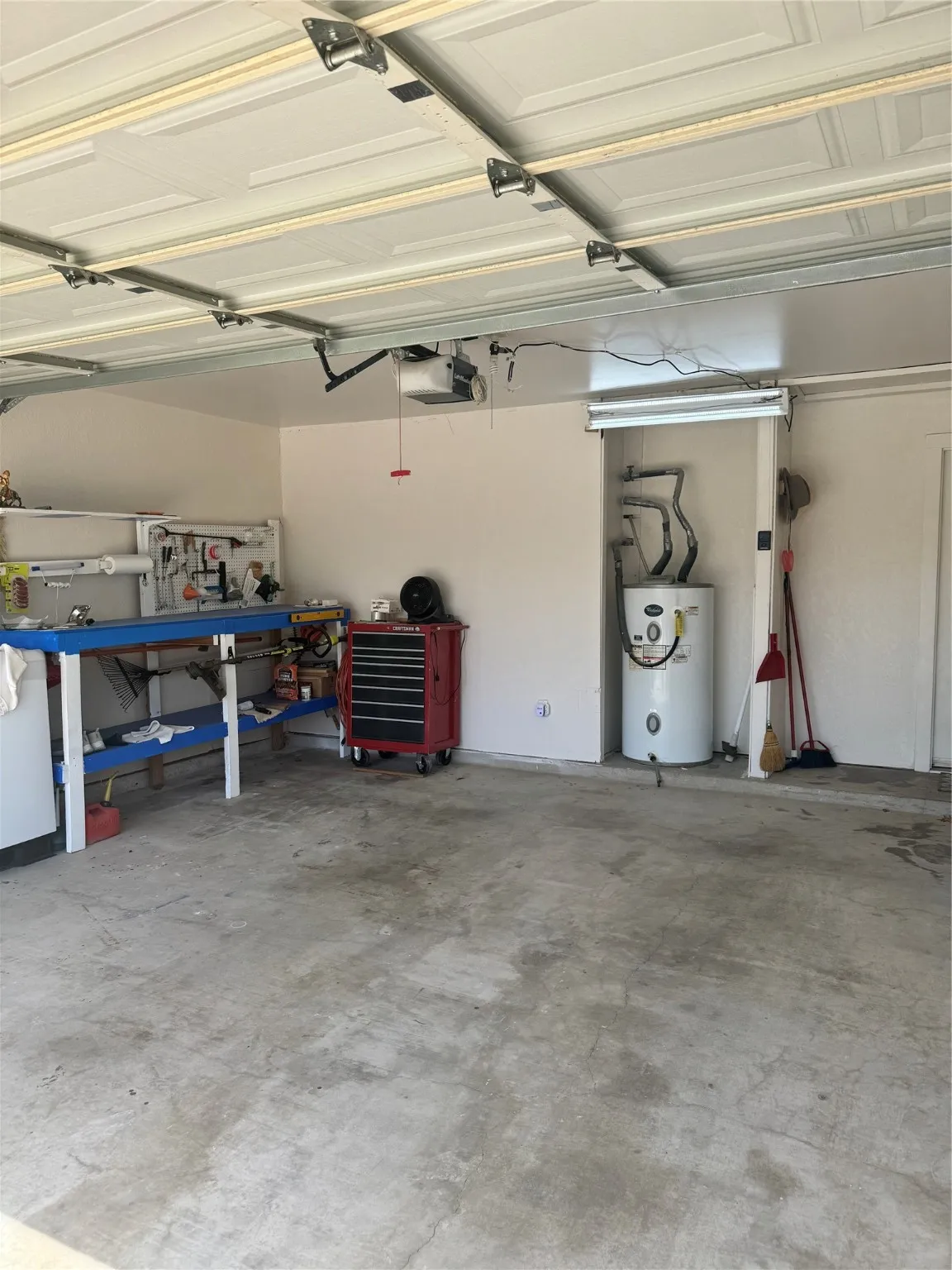 Garage with water heater, a garage door opener, and a workshop area