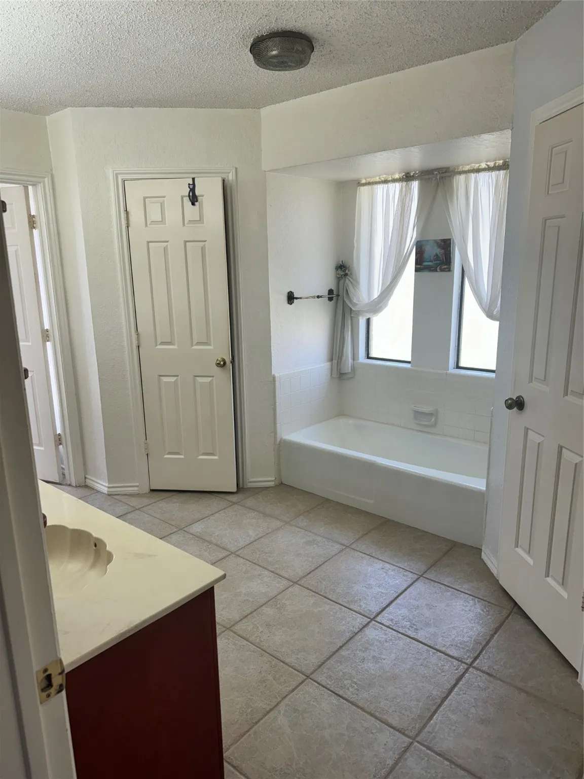 Full bathroom with vanity, a bath, and a textured ceiling
