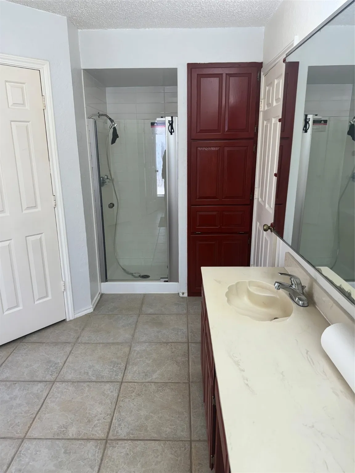 Full bath with vanity, a textured ceiling, baseboards, and a shower stall
