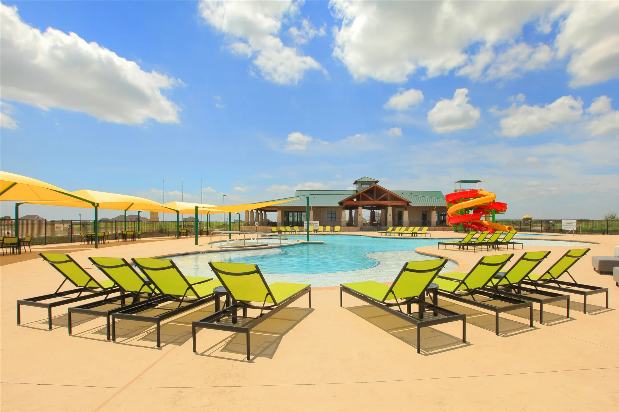 Expansive community pool area featuring a resort-style swimming pool, a vibrant waterslide, and multiple shaded lounge areas