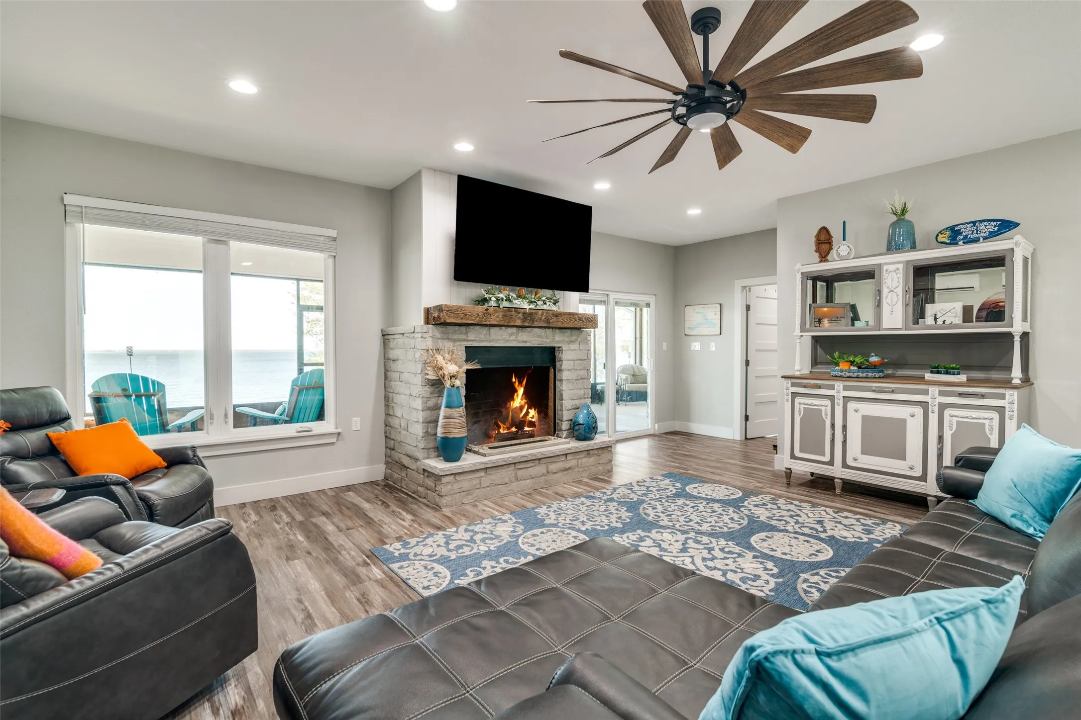Living area with lake view, recessed lighting, a brick fireplace, ceiling fan, and finished floors