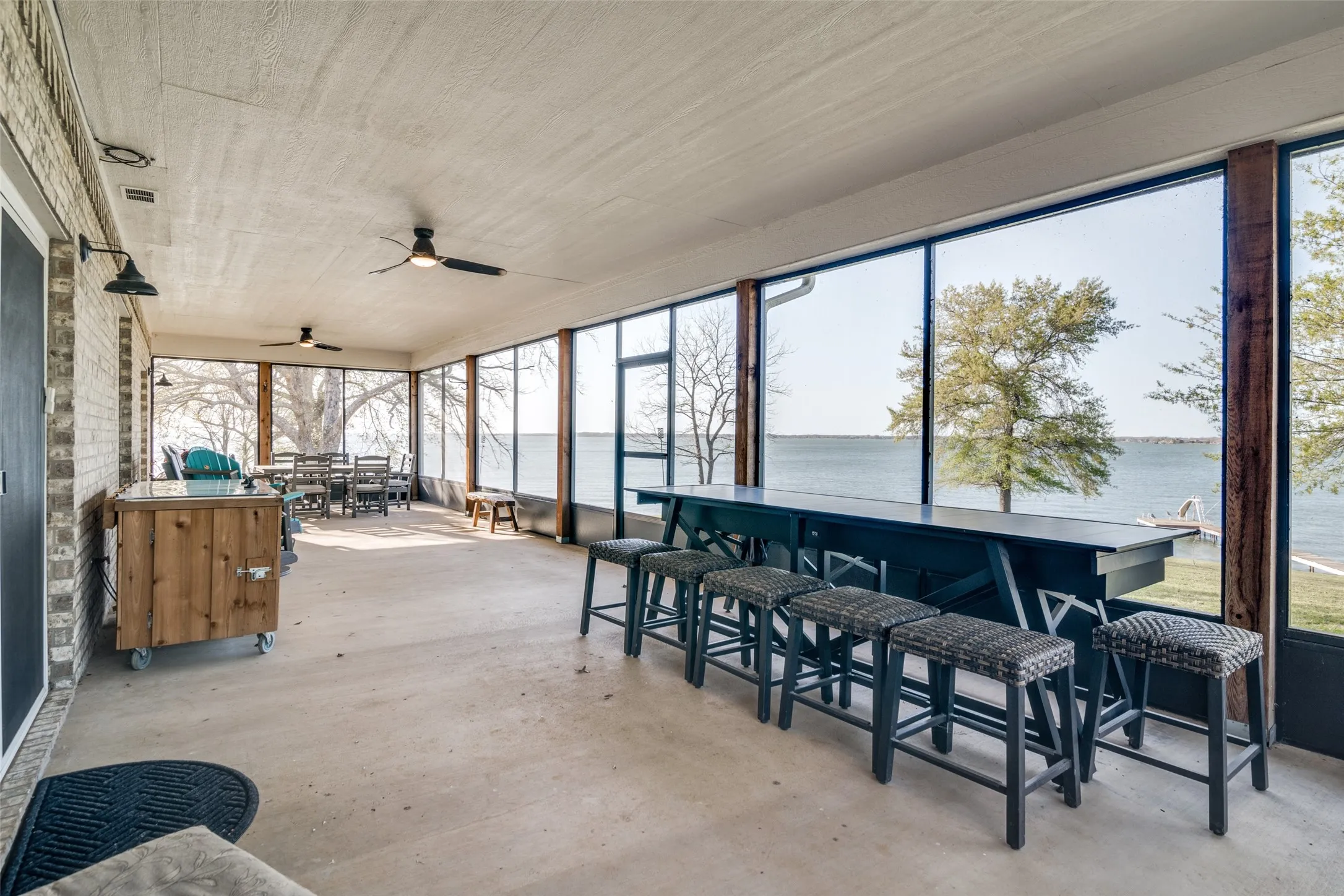 Sunroom with picturesque open water view, outdoor dining area, outdoor dry bar, and ceiling fan