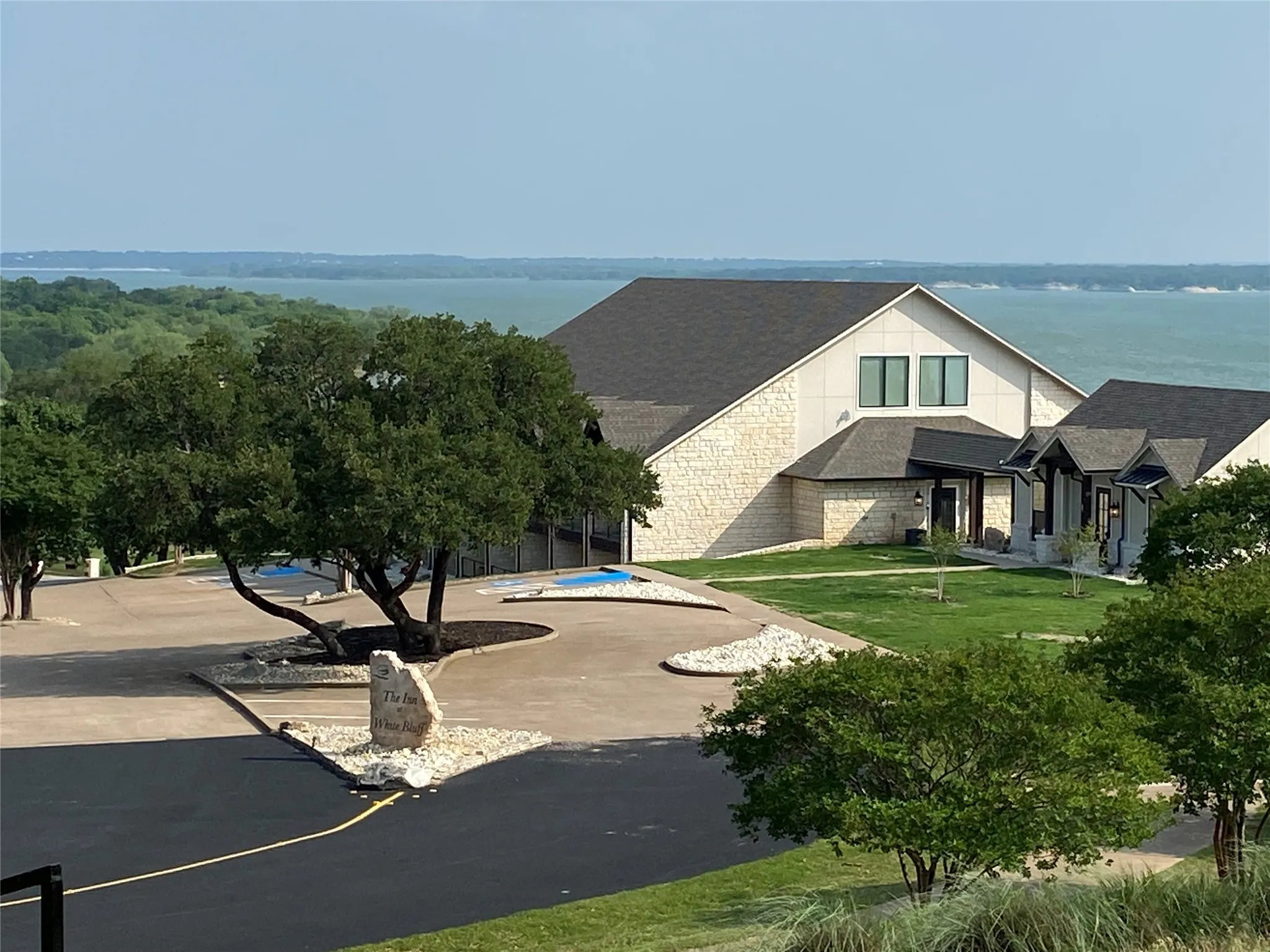 View of front facade with stone siding, a front yard, and roof with shingles