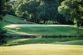 View of home's community with view of golf course, a lawn, and view of wooded area