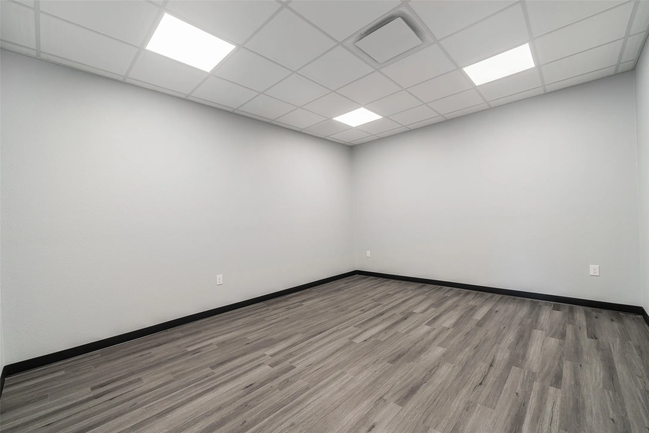 Empty room with a paneled ceiling, baseboards, and wood finished floors