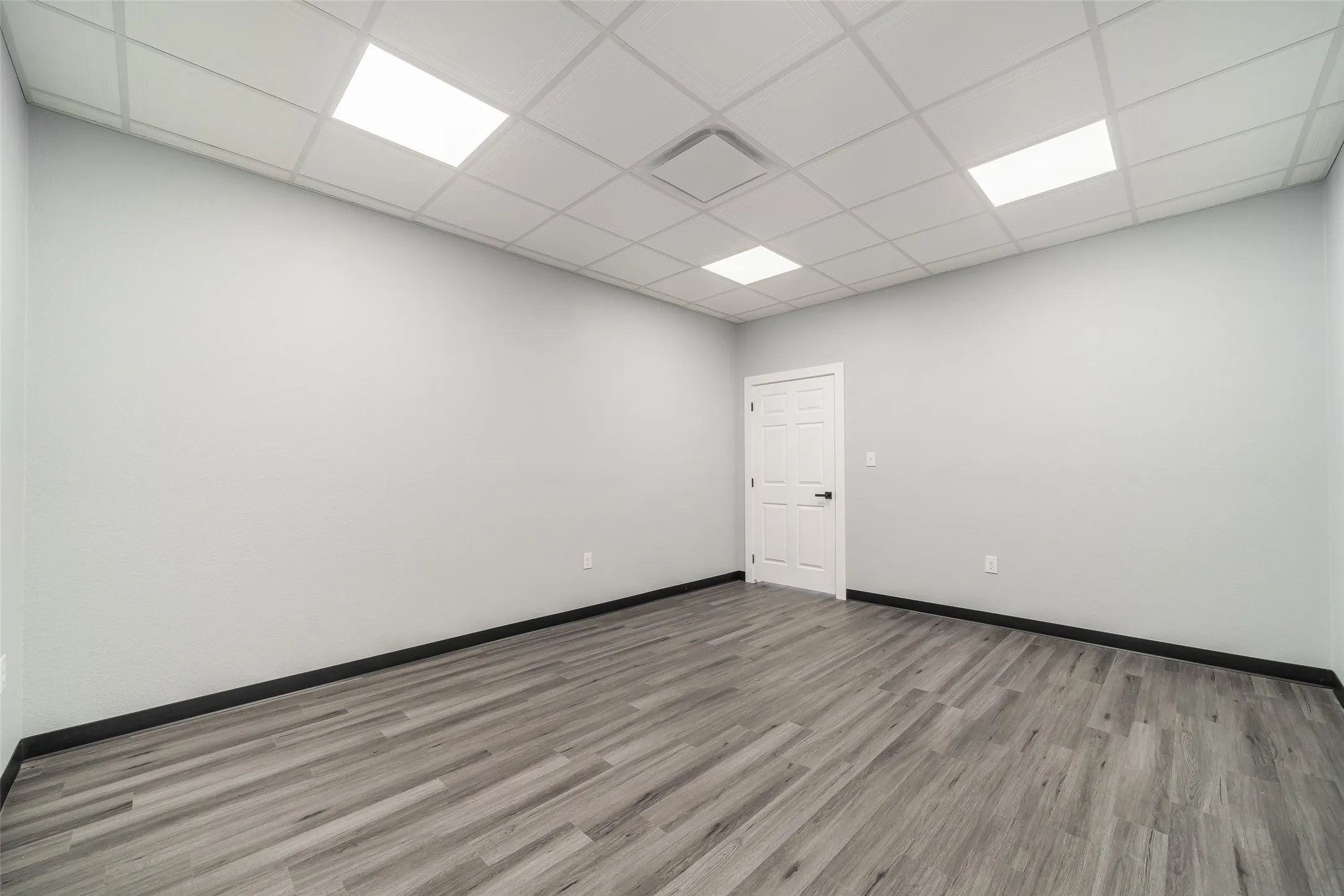 Unfurnished room with baseboards, light wood-type flooring, and a paneled ceiling