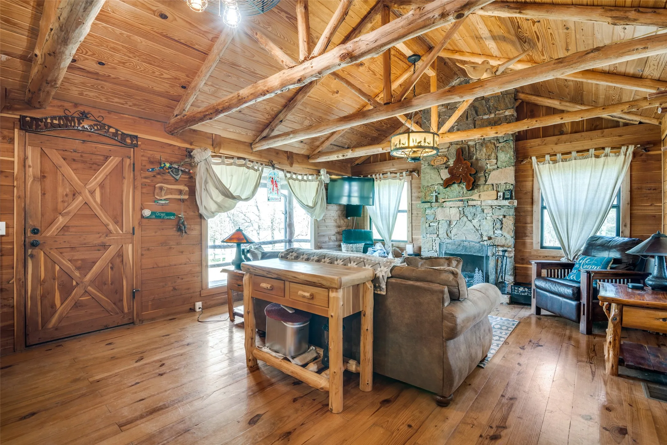 Living area with vaulted ceiling with beams, light wood finished floors, and a healthy amount of sunlight