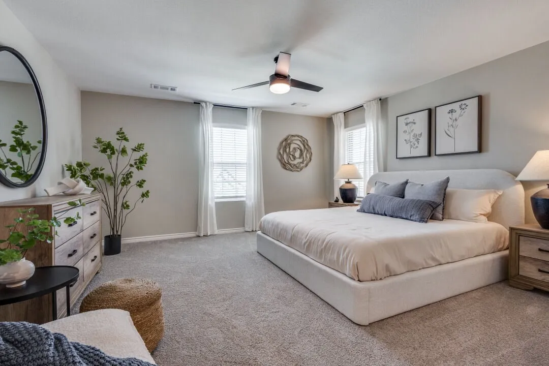 Carpeted bedroom with baseboards, visible vents, and ceiling fan