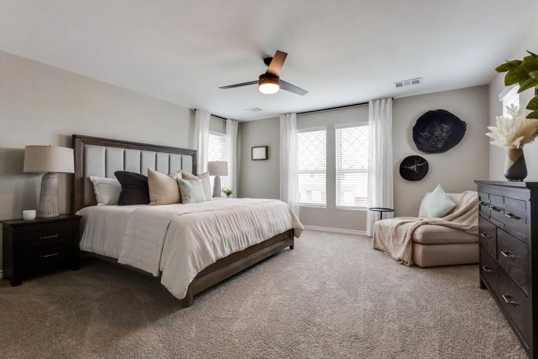 Bedroom with carpet flooring, ceiling fan, visible vents, and multiple windows