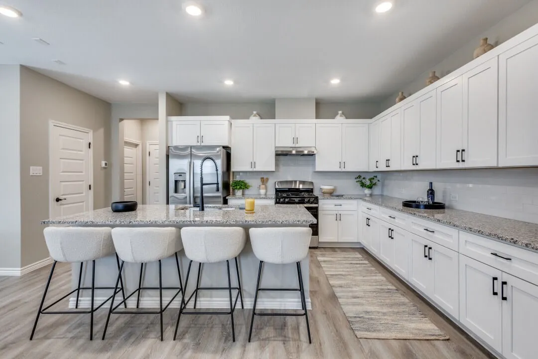 Kitchen with light wood finished floors, stainless steel appliances, tasteful backsplash, white cabinetry, and an island with sink
