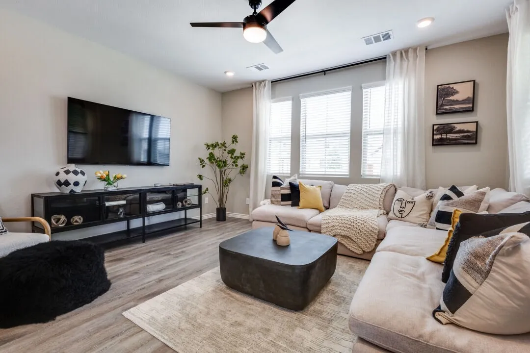 Living room with baseboards, visible vents, wood finished floors, and ceiling fan