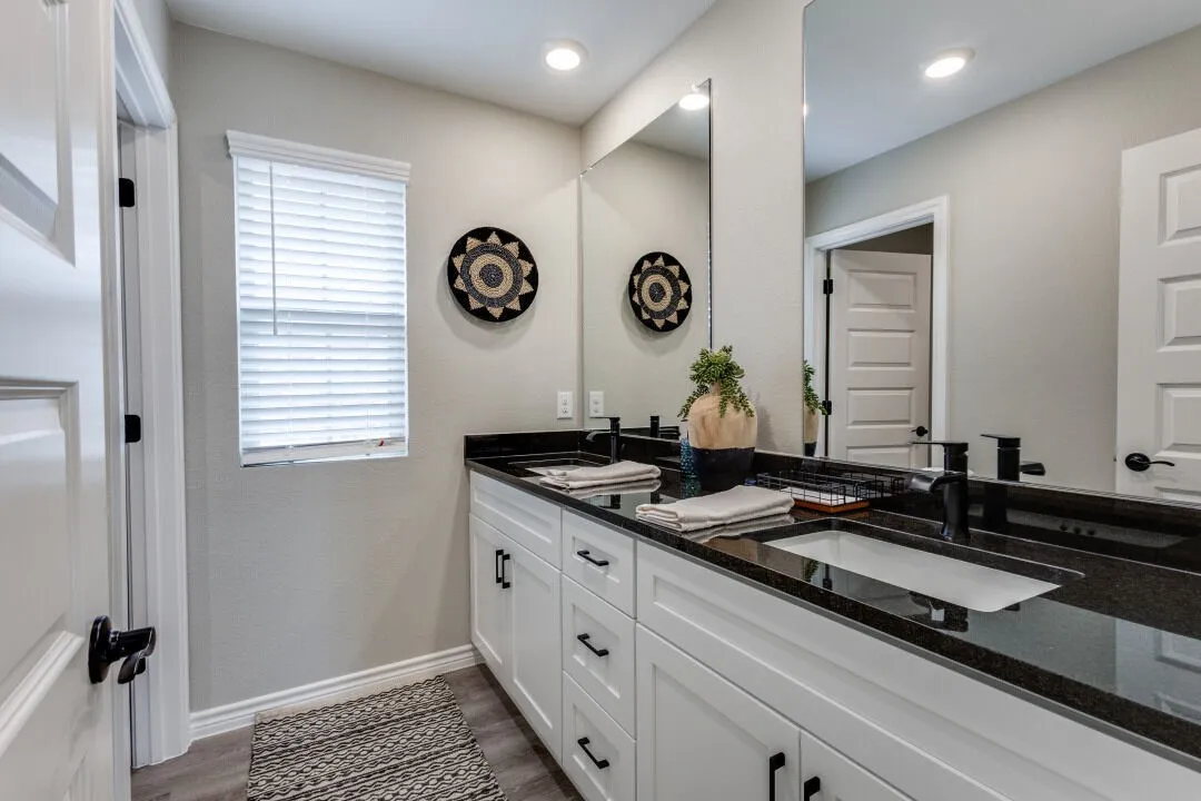 Full bathroom featuring baseboards, double vanity, a sink, and wood finished floors