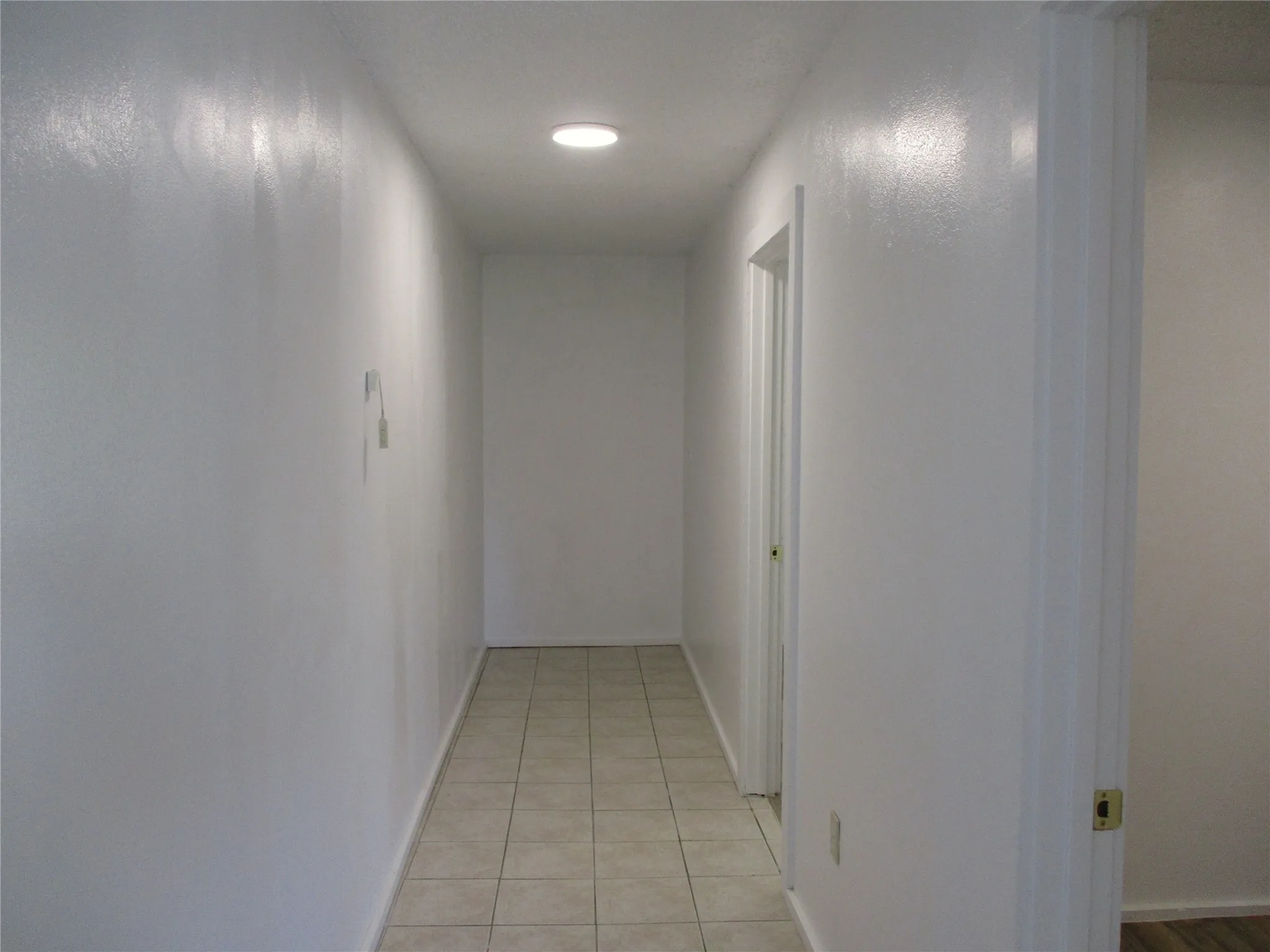 Corridor featuring light tile patterned floors and baseboards