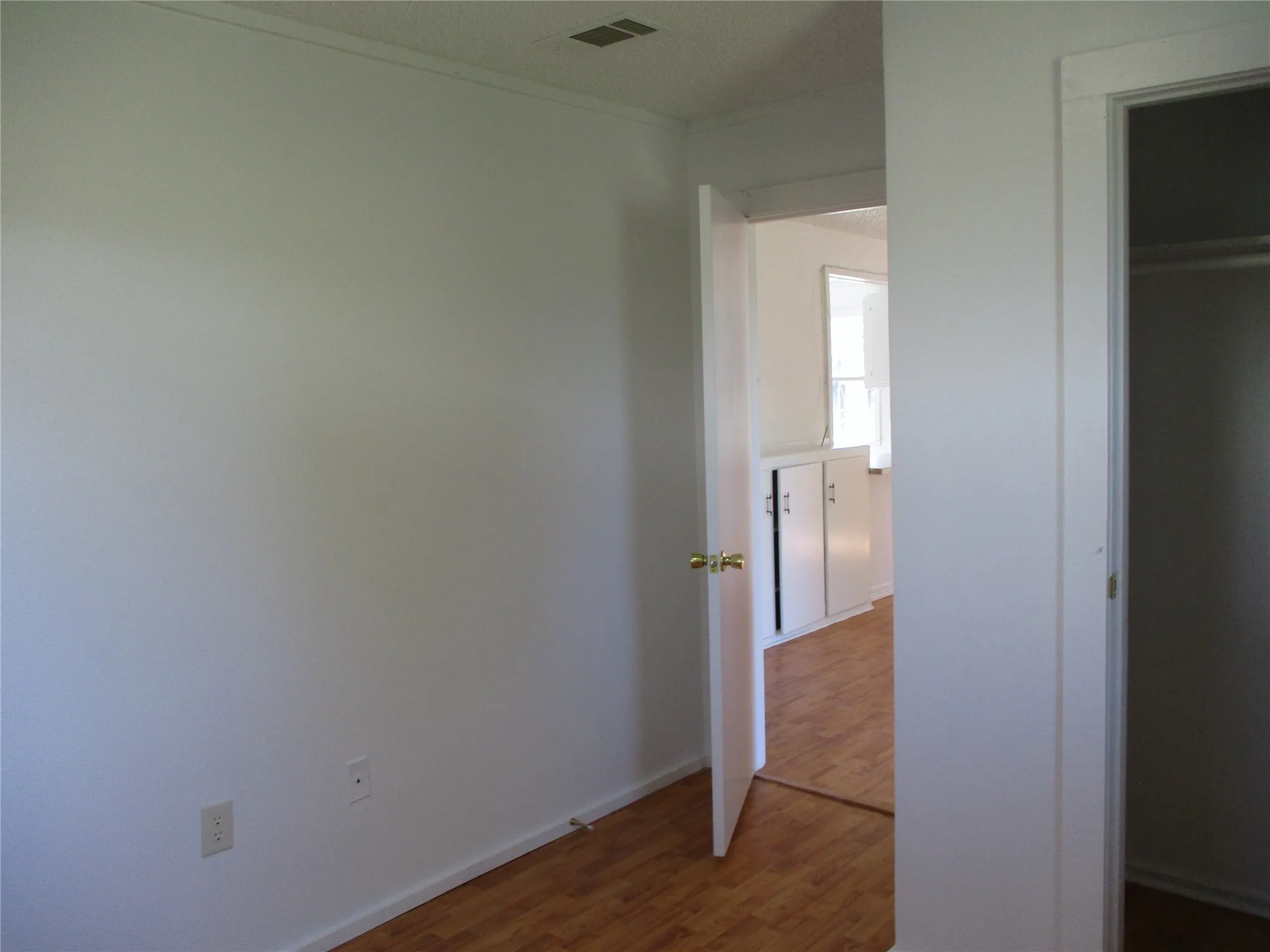 Unfurnished bedroom with visible vents, baseboards, a closet, and wood finished floors