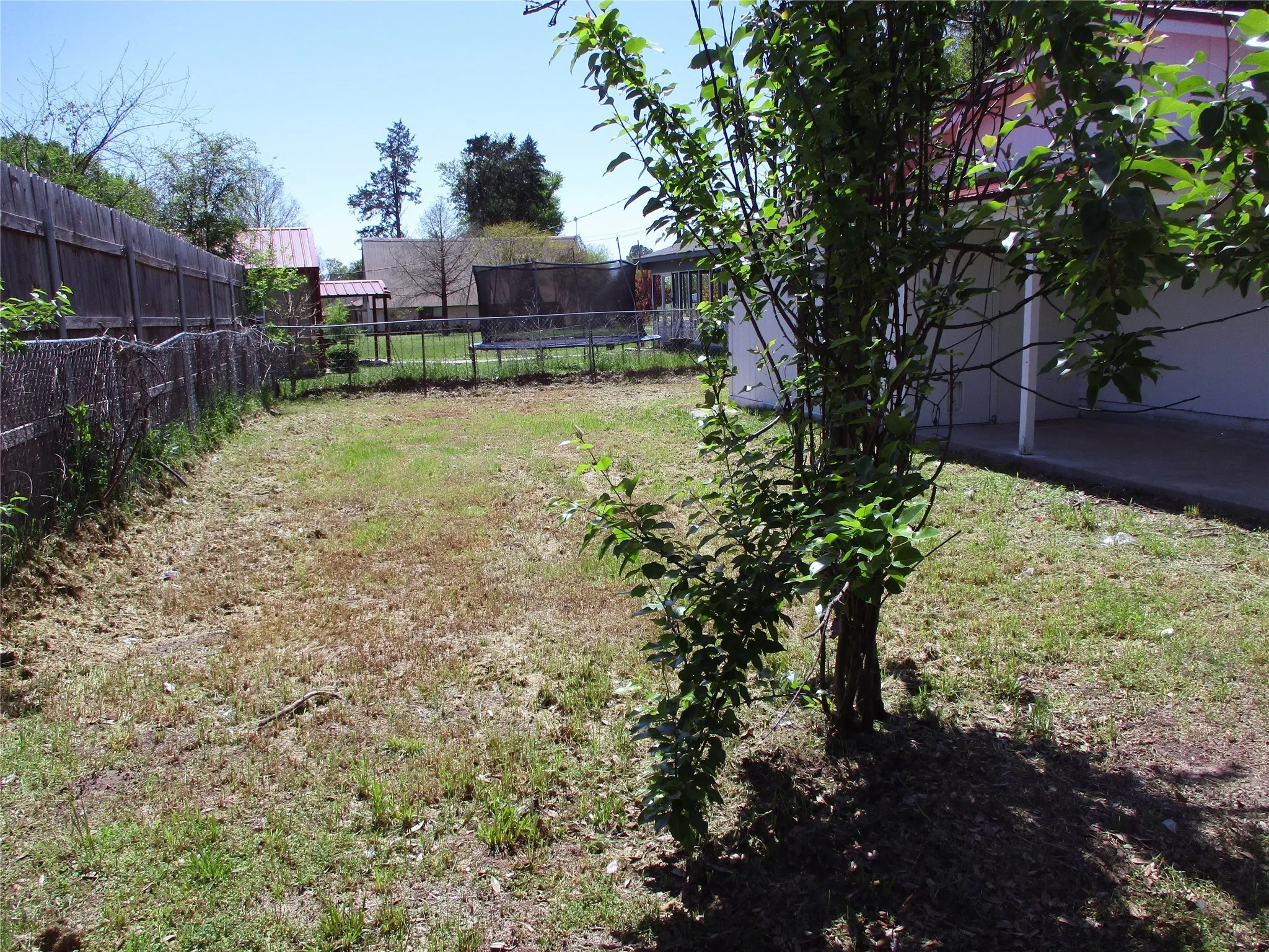 View of yard with a trampoline and a fenced backyard